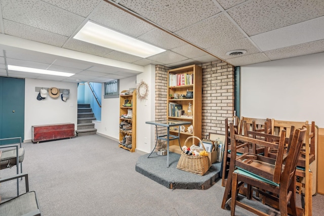 finished below grade area featuring carpet flooring, visible vents, baseboards, stairs, and a paneled ceiling