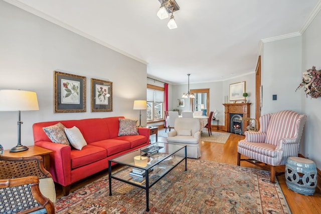 living room with baseboards, a warm lit fireplace, wood finished floors, and ornamental molding