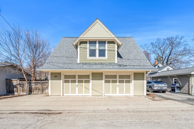 view of front of house featuring fence, roof with shingles, and a detached garage