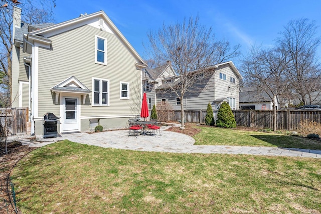rear view of property featuring a lawn, a fenced backyard, and a patio area