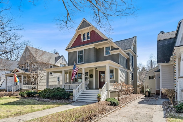 view of front facade with covered porch and a shingled roof