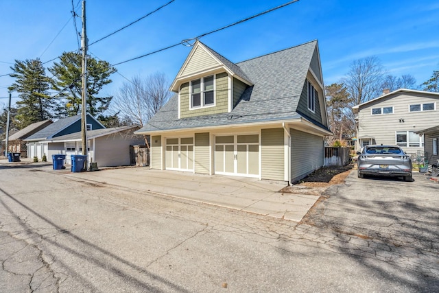 view of front of house featuring aphalt driveway, fence, and roof with shingles