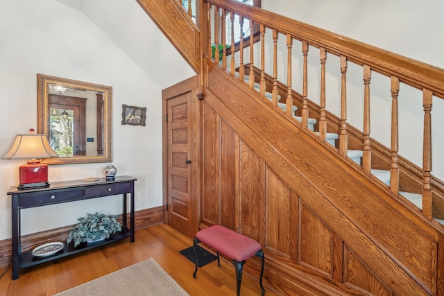 stairs with baseboards, lofted ceiling, visible vents, and wood finished floors