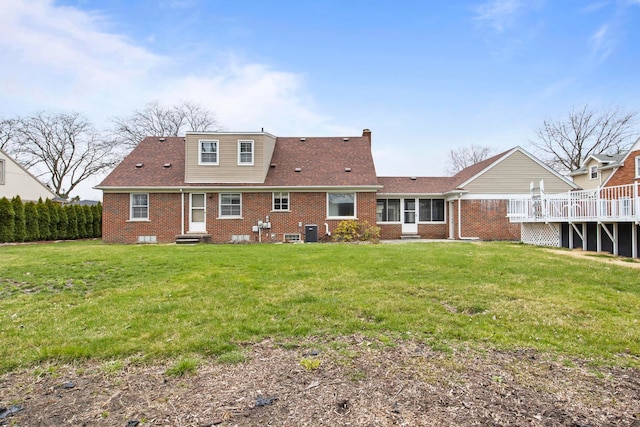 rear view of property with central air condition unit, entry steps, a lawn, and brick siding