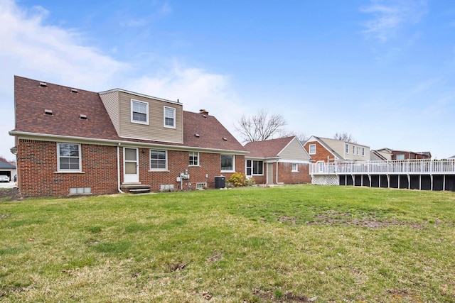 rear view of house featuring brick siding, entry steps, cooling unit, and a yard