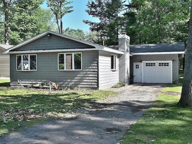 view of side of home with a chimney, an attached garage, and aphalt driveway
