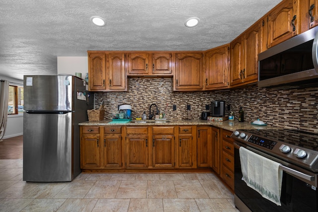 kitchen featuring a sink, decorative backsplash, brown cabinets, and appliances with stainless steel finishes