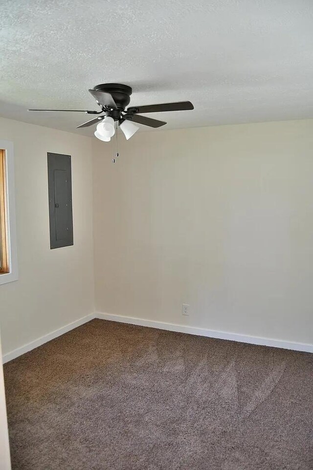 unfurnished room featuring carpet flooring, baseboards, a textured ceiling, ceiling fan, and electric panel