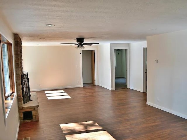 unfurnished living room featuring baseboards, wood finished floors, ceiling fan, and a textured ceiling