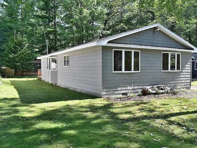 view of side of property with crawl space and a yard