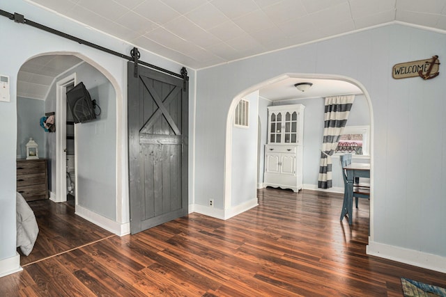 spare room with visible vents, lofted ceiling, a barn door, and wood finished floors