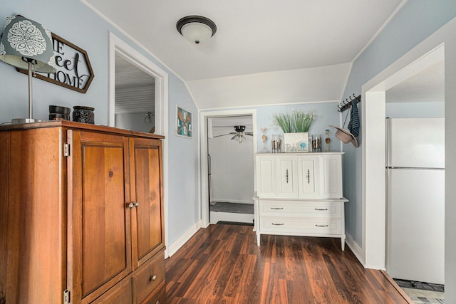 interior space featuring baseboards, vaulted ceiling, and dark wood finished floors