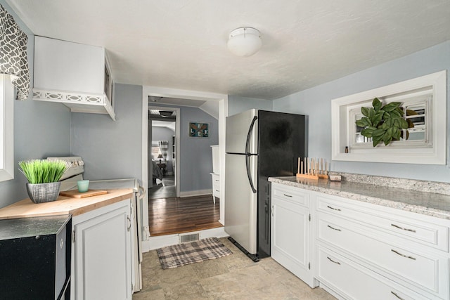 kitchen with wood counters, white cabinets, electric range oven, and freestanding refrigerator
