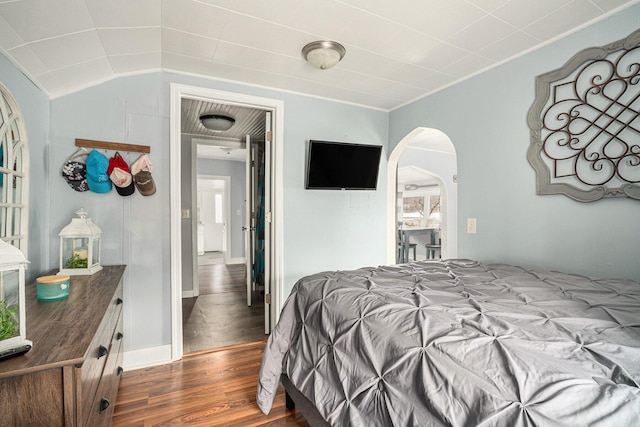 bedroom featuring arched walkways, lofted ceiling, and dark wood finished floors