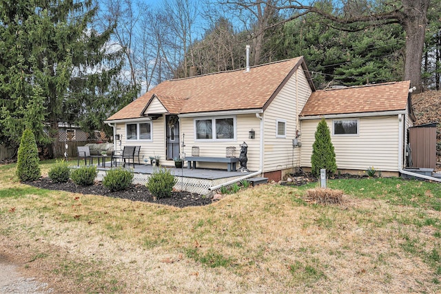 back of property featuring roof with shingles, fence, and a lawn