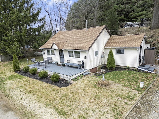 rear view of property with roof with shingles, a deck, fence, and a yard