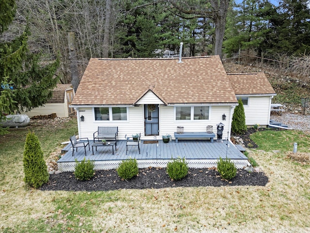 rear view of house with a lawn, a shingled roof, and a deck