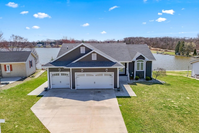 traditional home featuring concrete driveway, an attached garage, a water view, a front lawn, and a shingled roof