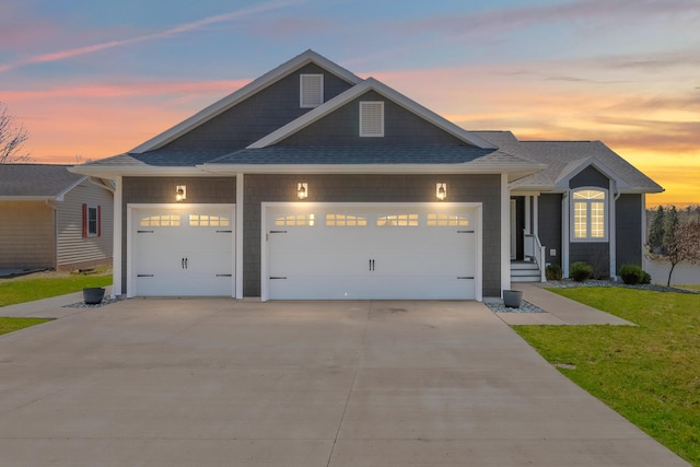 view of front of property with a lawn, roof with shingles, an attached garage, and concrete driveway
