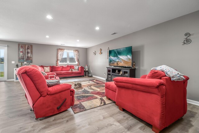 living room with baseboards, visible vents, and wood finished floors