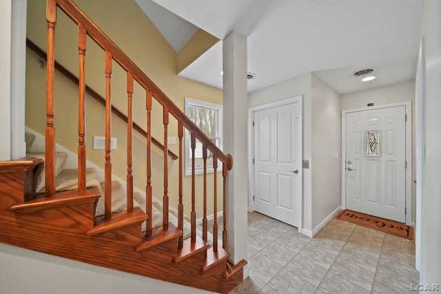 foyer with stairway, baseboards, light tile patterned flooring, and visible vents