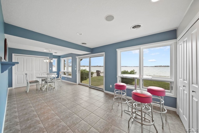 interior space with an inviting chandelier, a water view, and visible vents