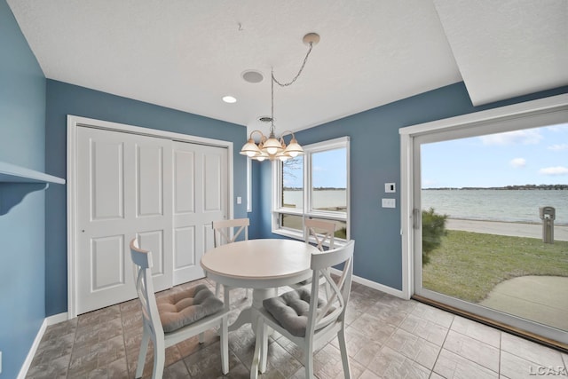dining space with baseboards, a water view, and a chandelier
