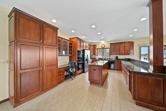 kitchen featuring a sink, built in study area, recessed lighting, glass insert cabinets, and black appliances