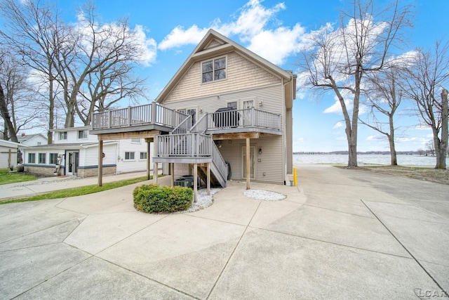 rear view of property featuring a deck with water view, stairs, and central AC unit