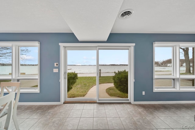 entryway featuring a water view, baseboards, visible vents, and plenty of natural light