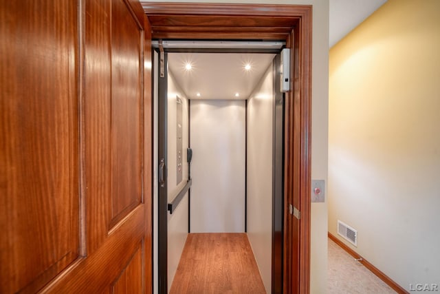 hall with visible vents, recessed lighting, and elevator