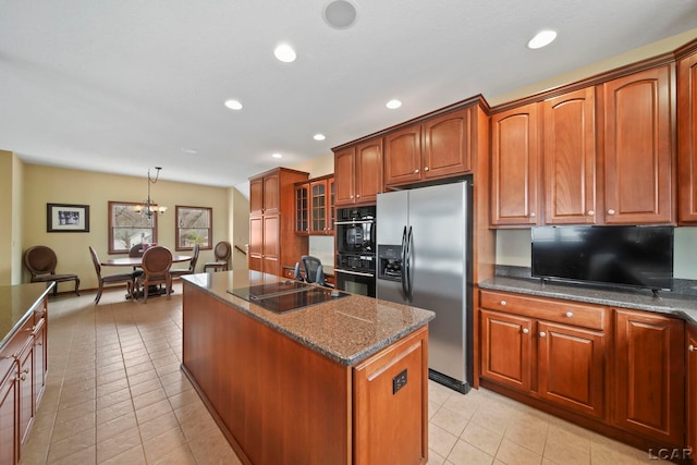 kitchen featuring brown cabinetry, a center island with sink, recessed lighting, light tile patterned floors, and black appliances