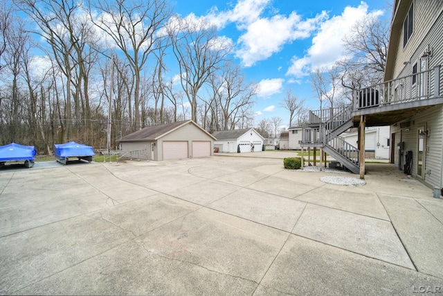view of patio / terrace featuring a detached garage, a deck, stairway, and an outbuilding