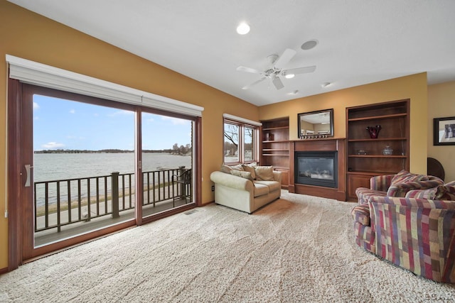 3387 Round Lake Hwy, Manitou Beach, MI 49253 - living area with a glass covered fireplace, a water view, a ceiling fan, and carpet floors