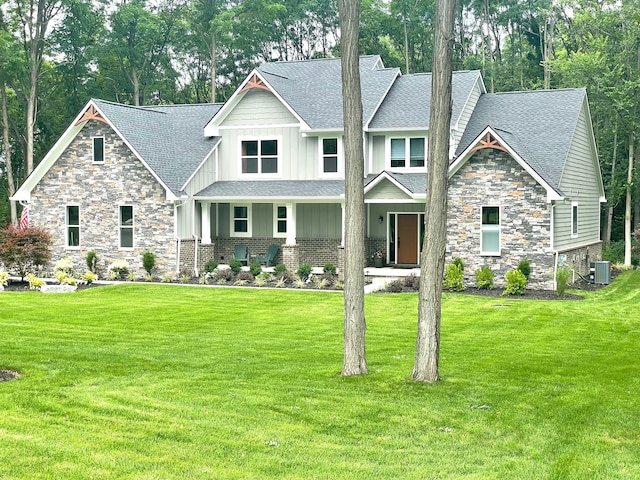 view of front of house with a front yard, stone siding, roof with shingles, board and batten siding, and central AC unit