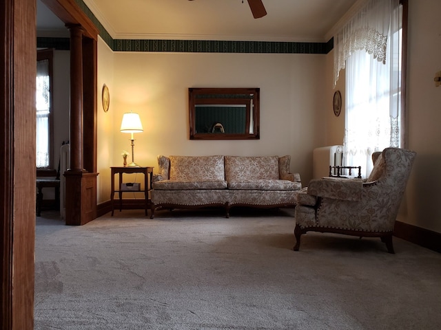 carpeted living room with crown molding, baseboards, ceiling fan, and ornate columns