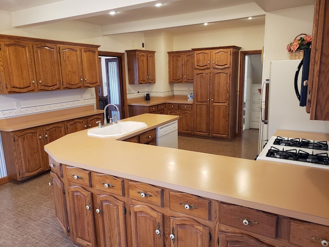 kitchen with light countertops, a sink, beam ceiling, dishwasher, and brown cabinetry