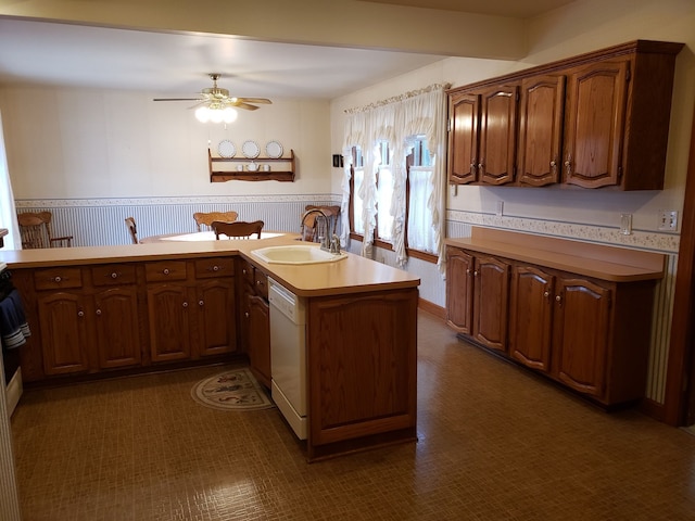 kitchen featuring a wainscoted wall, wallpapered walls, a ceiling fan, a sink, and white dishwasher