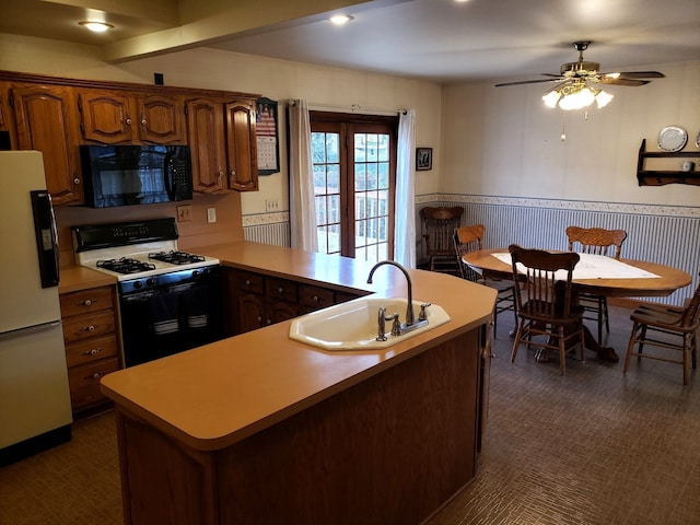 kitchen featuring a sink, black microwave, white refrigerator with ice dispenser, wainscoting, and gas range