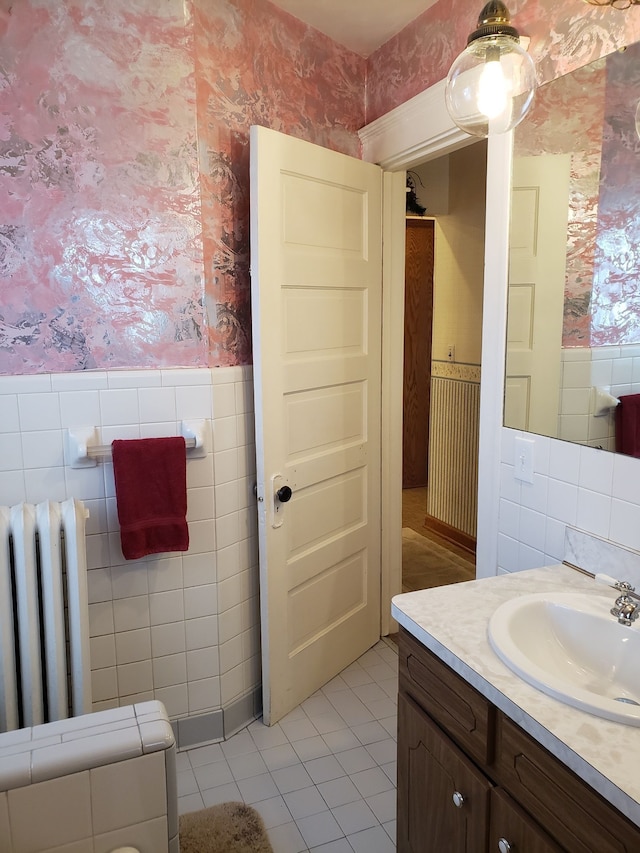 bathroom with radiator heating unit, wallpapered walls, vanity, and wainscoting