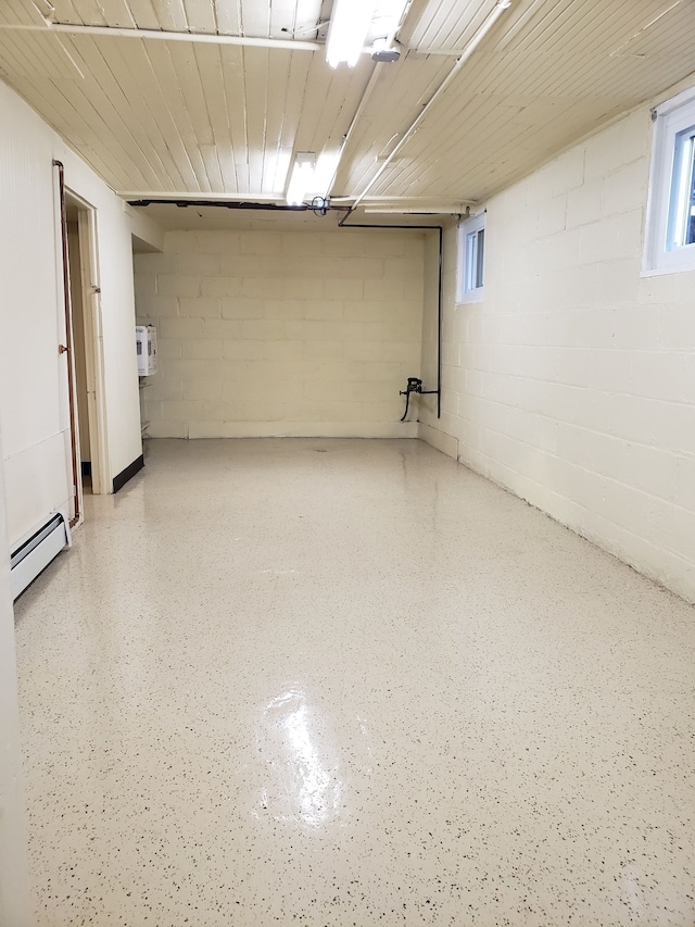 basement featuring wood ceiling, concrete block wall, and baseboard heating
