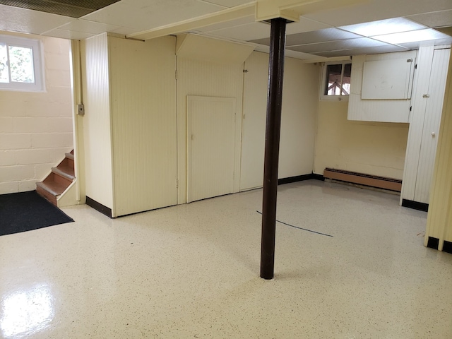 basement with baseboards, a baseboard heating unit, and concrete block wall