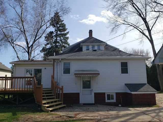 back of property with a chimney and a deck