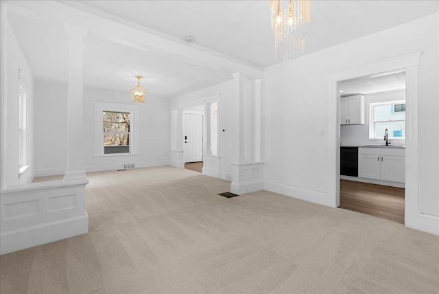 1026 S Jackson St, Jackson, MI 49203 - unfurnished living room with a sink, carpet floors, ornate columns, and a notable chandelier