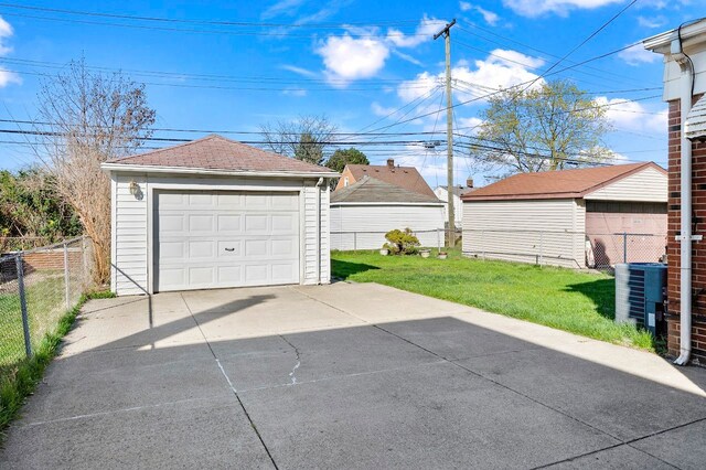 detached garage with fence, central AC unit, and driveway
