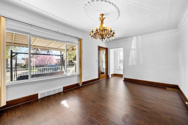 unfurnished dining area featuring an inviting chandelier, visible vents, wood finished floors, and a healthy amount of sunlight