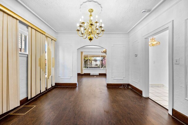 unfurnished dining area featuring visible vents, wood finished floors, an inviting chandelier, and arched walkways