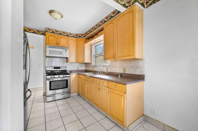 kitchen featuring white microwave, stainless steel gas stove, dark countertops, backsplash, and a sink