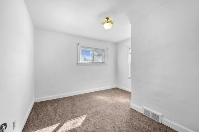 carpeted spare room featuring visible vents and baseboards