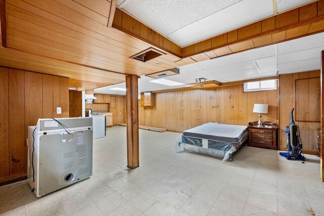 below grade area featuring washing machine and dryer, electric panel, wood walls, and tile patterned floors